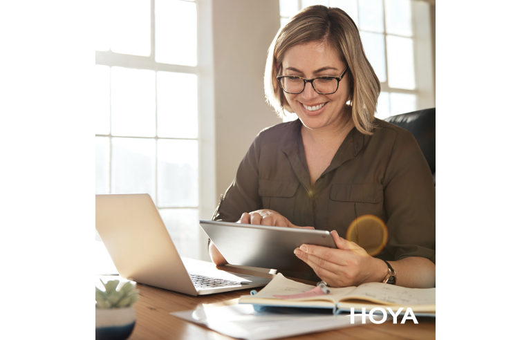 een vrouw met bril werkt op een laptop en op een tablet_hoya brillenglazen
