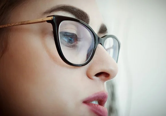 een jonge vrouw met zwarte bril met blauwfilter glazen werk op een scherm